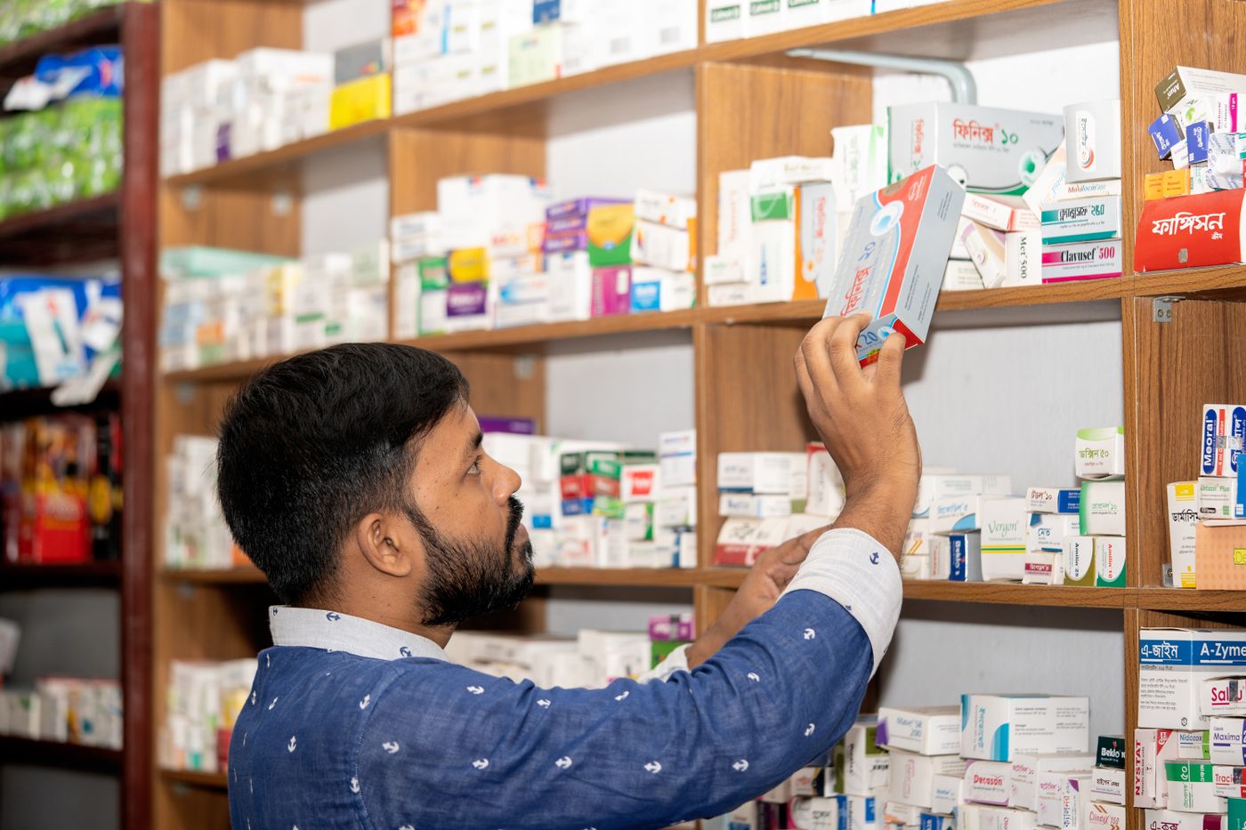 Pharmacist standing beside well-stocked shelves in a modern pharmacy